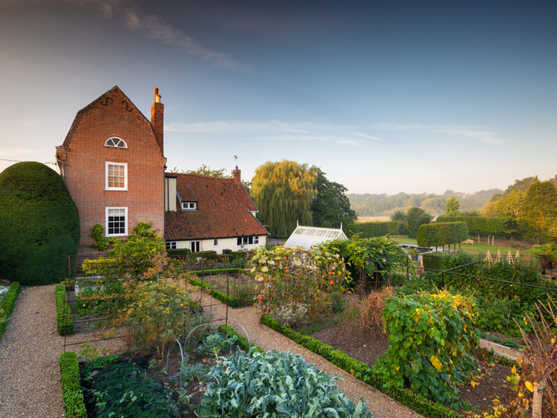 View from within formal walled vegetable garden to Mansard House and garden beyond in garden designer Thomas Hoblyn's own garden, Suffolk.